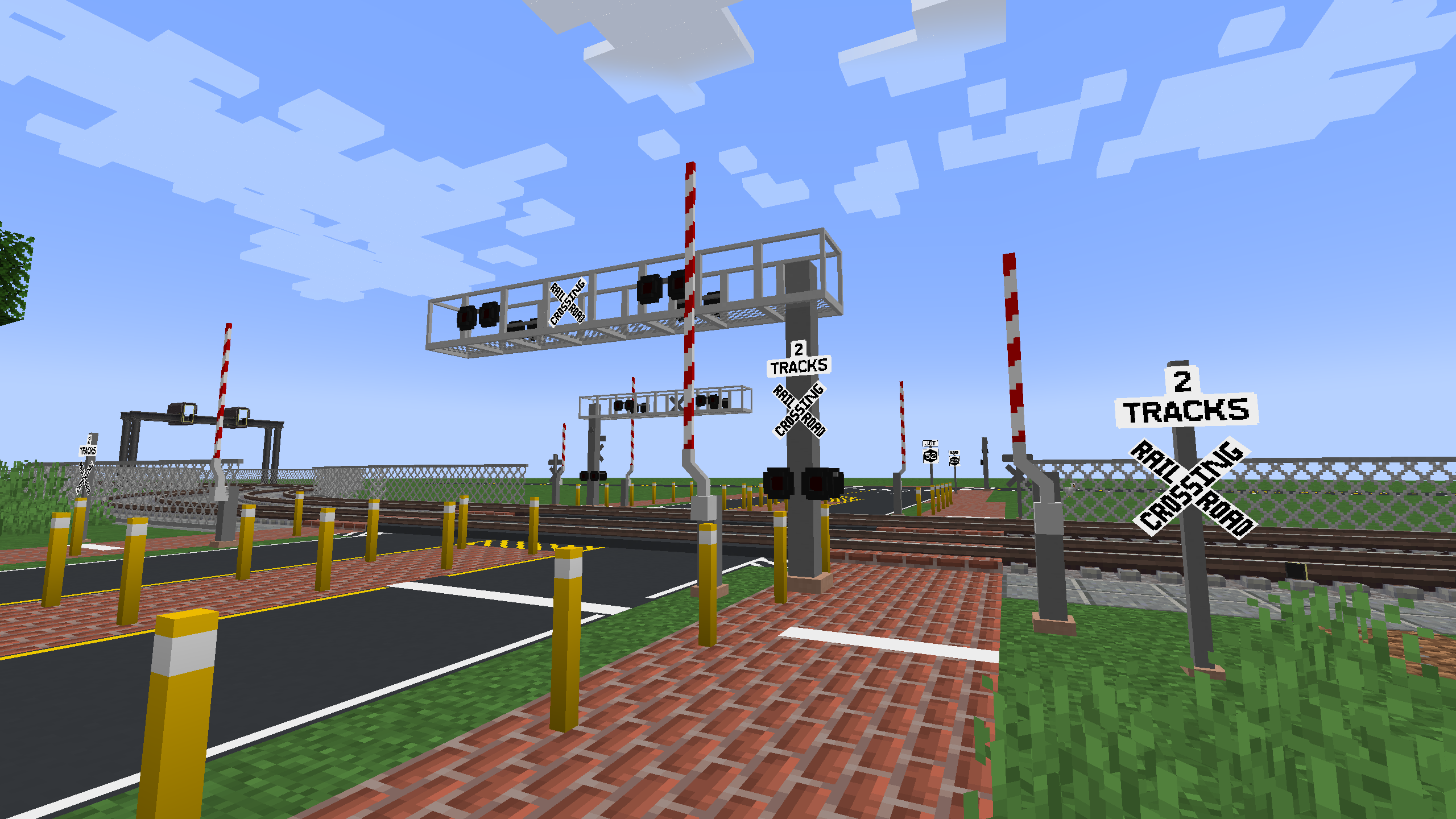 A railroad crossing, featuring gate arms, lights, two tracks, and various other road features, such as markings and signage